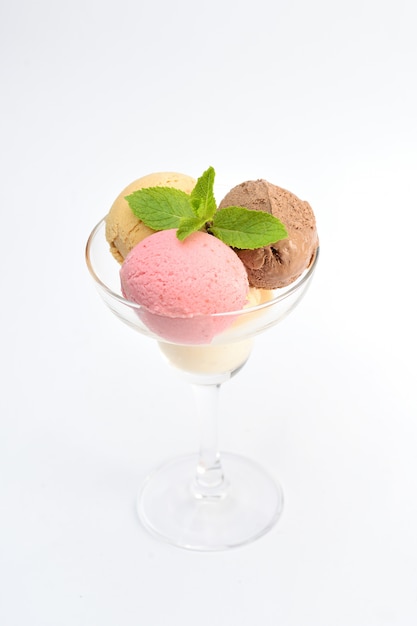 Bolas de helado con menta en un vaso transparente, sobre blanco