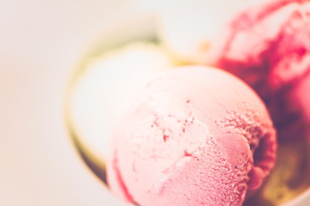 Bolas de helado de vainilla y fresa en una taza blanca.