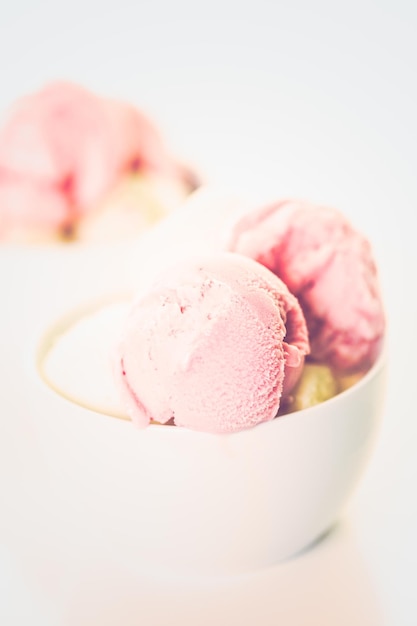 Bolas de helado de vainilla y fresa en una taza blanca.