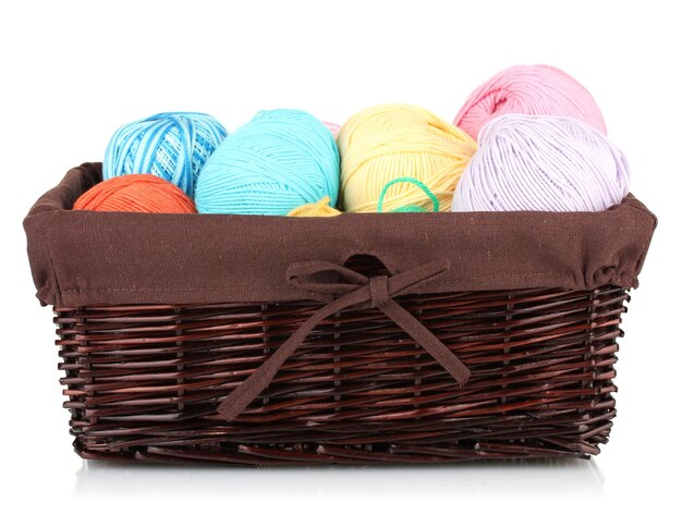 Bolas de hilo de colores en una canasta de mimbre aisladas en blanco