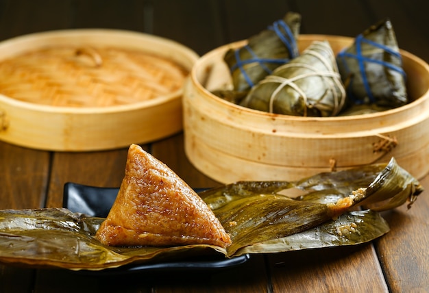 Foto bolas de masa de arroz zongzi y vaporizador de bambú sobre mesa de madera