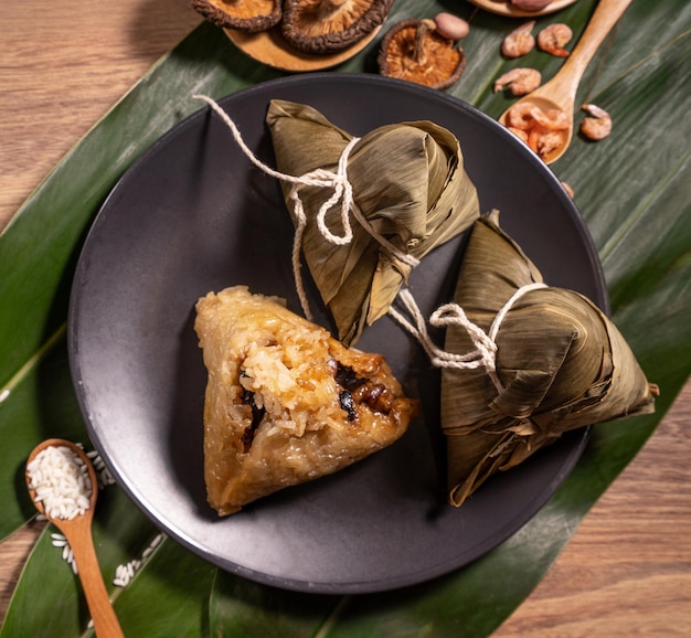 Bolas de masa hervida de arroz al vapor Zongzi en una mesa de madera hojas de bambú comida en el festival del bote del dragón duanwu concepto primer plano copia espacio vista superior plano