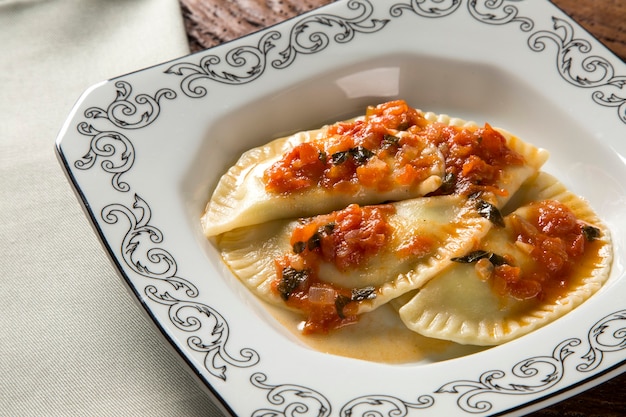 Bolas de masa hervida con carne con tomate en un plato - Pierogi