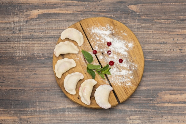 Bolas de masa hervida congeladas con cereza en una placa de madera sobre una superficie de madera