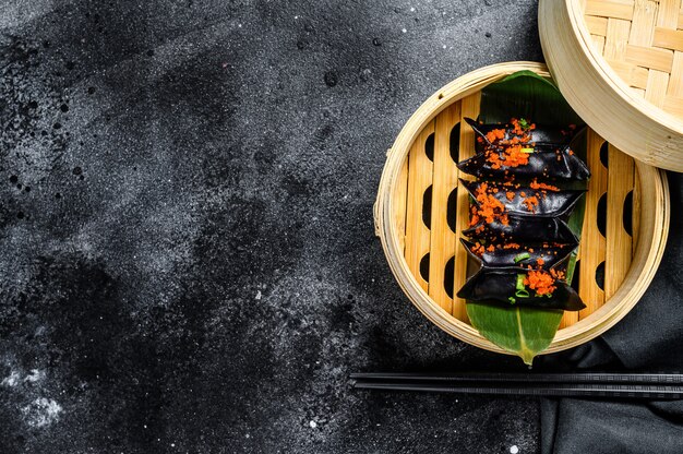 Bolas de masa hervida dim sum negras en vapor de bambú.