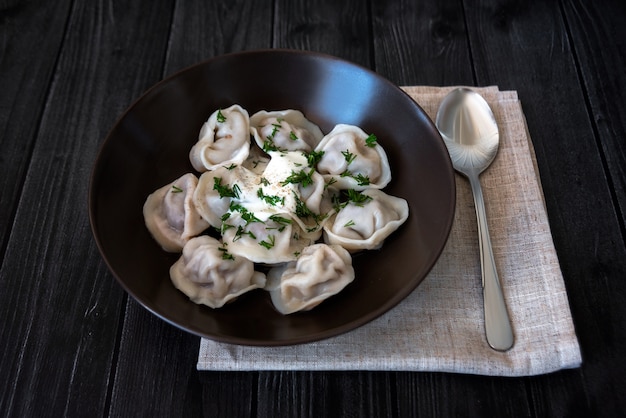 bolas de masa hervida en un plato marrón con hierbas y crema agria