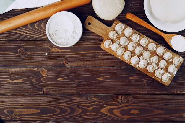 Bolas de masa hervida rusas rellenas crudas en tablero de madera