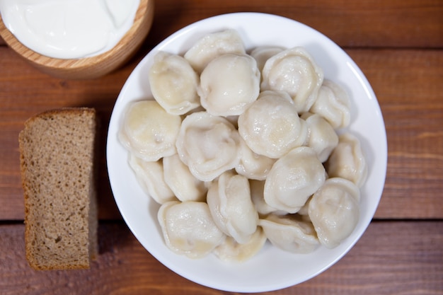 Bolas de masa en una mesa de madera con mostaza y crema agria, así como pan de centeno, ravioles.