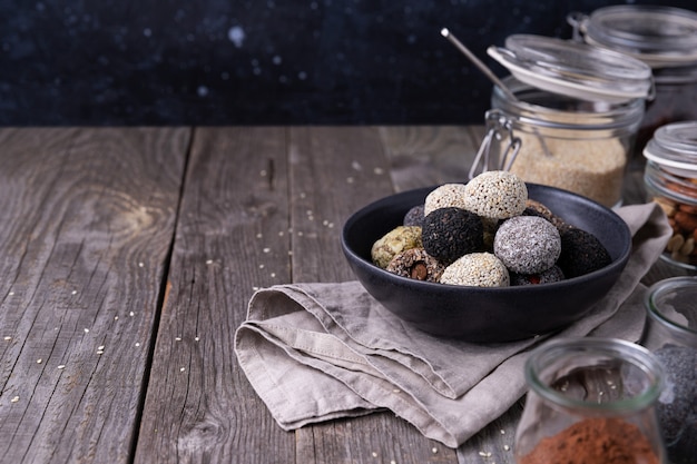 Bolas de mordiscos de energía cruda preparadas con ingredientes naturales sobre fondo de madera