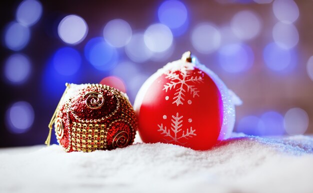 Bolas de Navidad adornadas en la nieve con luz de fondo azul.