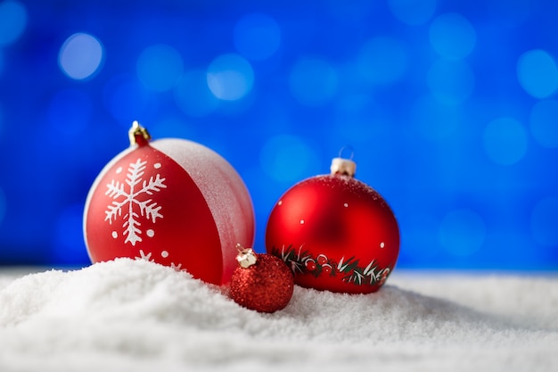 Bolas de Navidad adornadas en la nieve con luz de fondo azul.