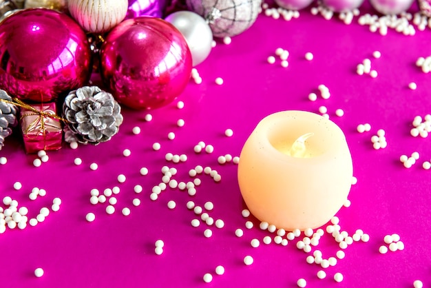 Bolas de Navidad y adornos sobre un fondo rosa.
