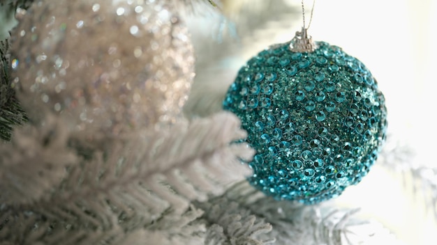 Bolas de Navidad azules y blancas colgando de la rama de abeto cubierto de nieve closeup