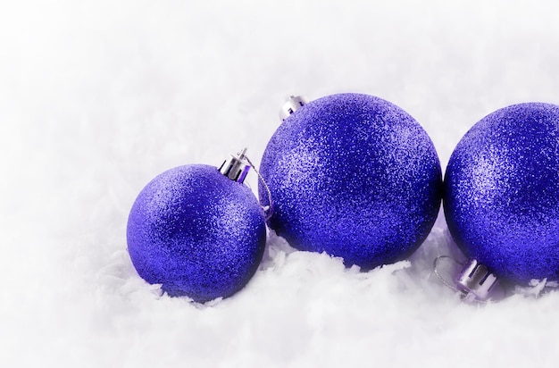 Bolas de Navidad azules en la nieve sobre un fondo blanco.