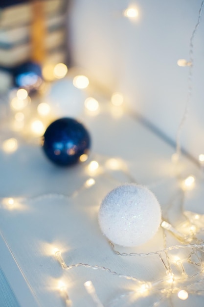 Bolas de Navidad blancas y azules con luces navideñas en un fondo blanco