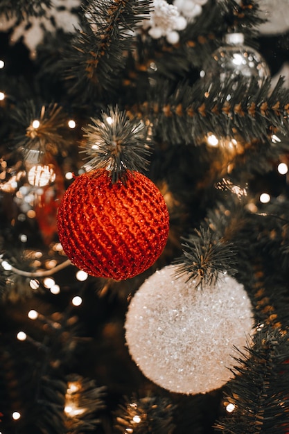 Bolas de Navidad brillantes blancas y rojas plateadas colgando del árbol de Navidad Efecto mágico de la guirnalda Bokeh