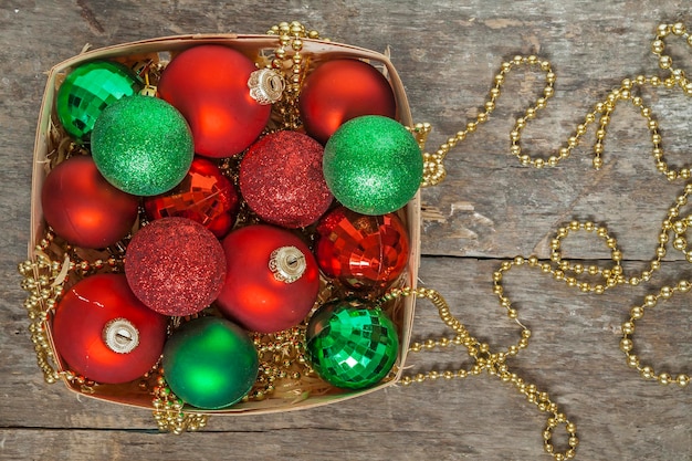 Bolas de Navidad cuentas de oro rojo y verde yacen en una cesta de madera vista superior de estilo vintage