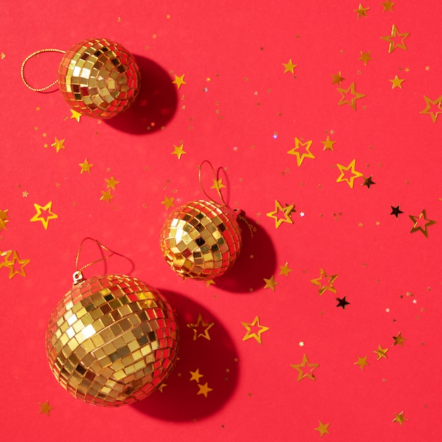 Foto bolas de navidad doradas con estrellas brillantes sobre fondo rojo.