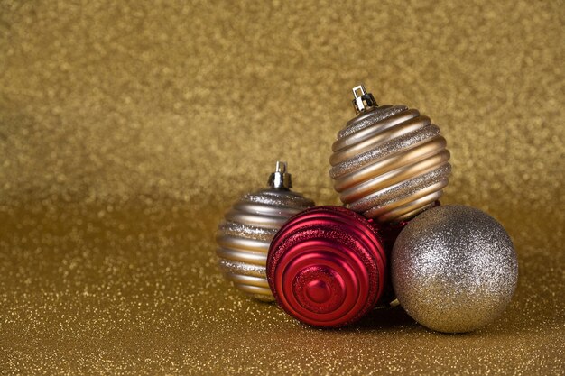 Bolas de Navidad doradas y rojas sobre un fondo dorado de brillo