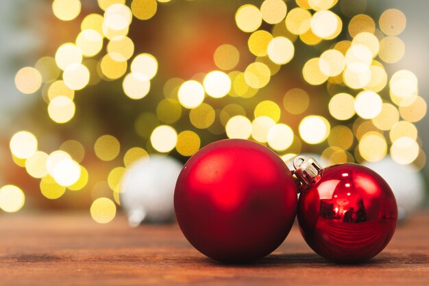 Bolas de Navidad en una mesa de madera contra luces bokeh brillantes borrosas