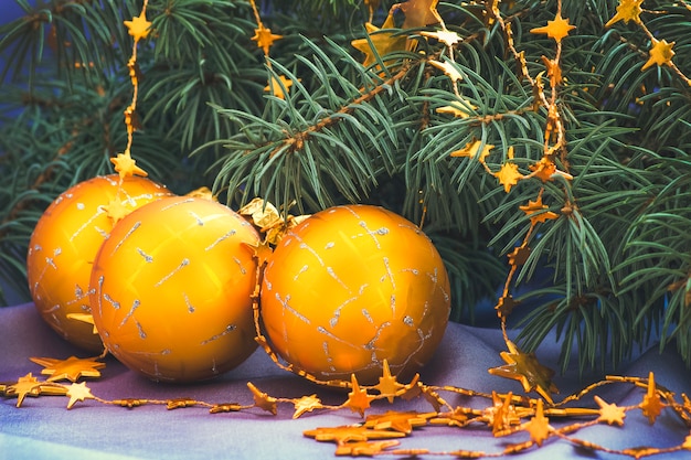Bolas de Navidad de oro y rama de árbol de hoja perenne.