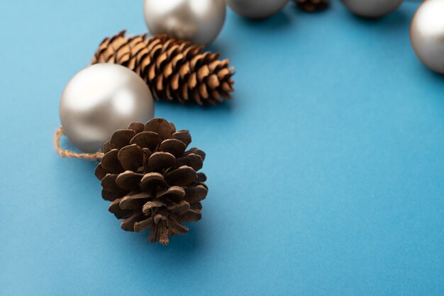 Bolas de Navidad plateadas y conos sobre un fondo azul claro