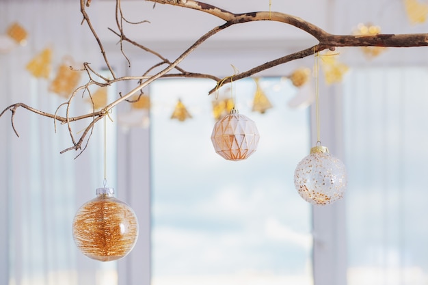 Bolas de Navidad en rama dorada en la ventana de fondo