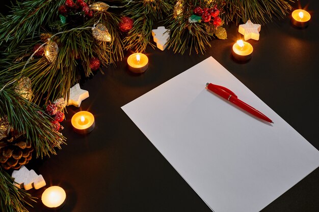 Bolas de Navidad rojas y cuaderno junto a la rama de abeto verde sobre fondo negro vista superior. Copie el espacio. Naturaleza muerta. Endecha plana. Año nuevo