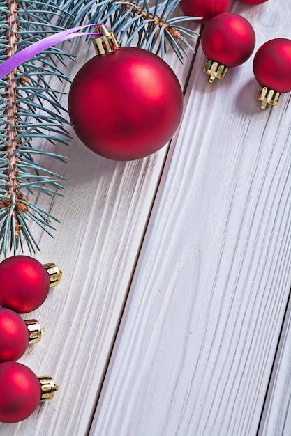 Bolas de navidad rojas y rama de pino en tablas de madera pintadas de blanco con espacio de copia