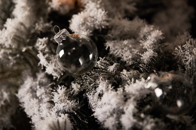 Bolas navideñas transparentes decorativas en ramas de abeto en la nieve