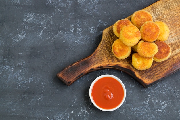 Bolas de papa fritas empanadas con salsa de tomate