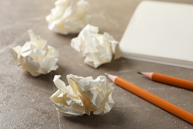 Bolas de papel, cuaderno y lápices sobre la mesa gris, de cerca