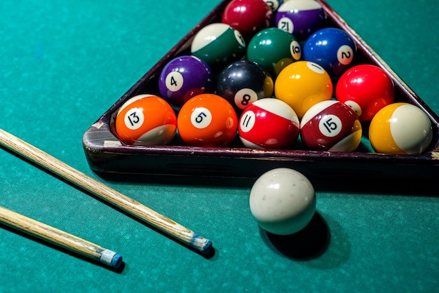 Bolas para bilhar ficam em triângulo em uma mesa verde antes do primeiro saque da bola