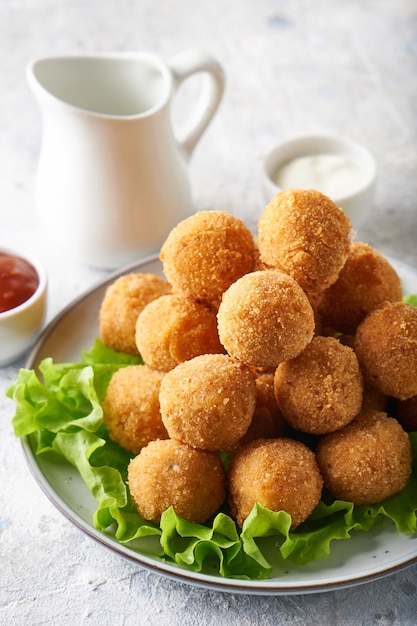 Bolas de queso, aperitivo con hierbas y salsas en un plato sobre una mesa gris