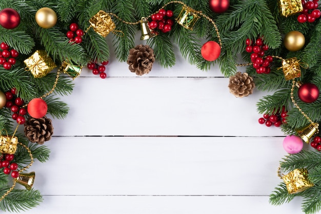 Bolas rojas de la caja de regalo de la Navidad con las ramas spruce, los conos del pino, las bayas rojas en el backg de madera