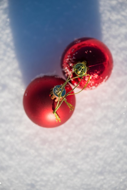 bolas rojas de navidad con largas sombras en la nieve fresca en un hermoso día soleado de invierno