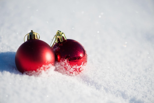 bolas rojas de navidad con largas sombras en la nieve fresca en un hermoso día soleado de invierno