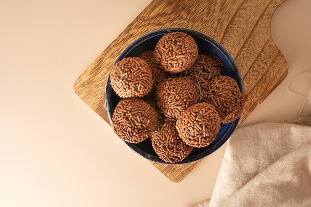 Foto bolas de trufa de chocolate brigadeiro dulces brasileños y escamas de chocolate vista aérea fondo beige
