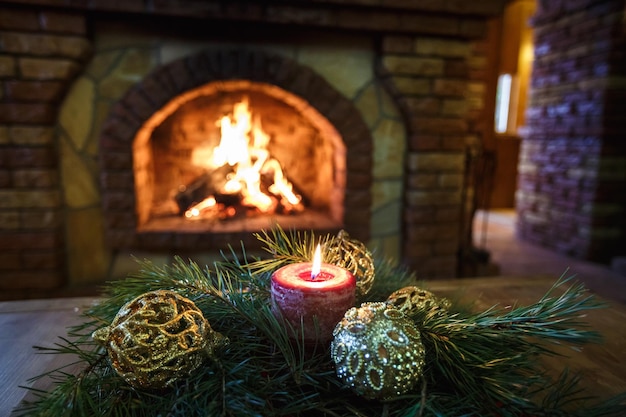 Bolas de velas navideñas y ramas de abeto en una mesa de madera cerca de la chimenea ambiente festivo