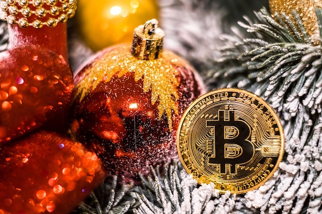 Bolas vermelhas de decorações de natal e moeda criptográfica de lembrança dourada bitcoin em galho decorativo de árvore de ano novo