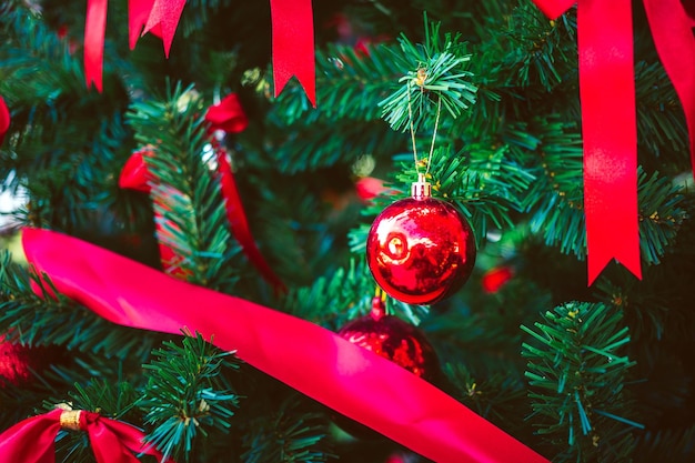 Bolas vermelhas de Natal e fita de laço vermelho adornam o fundo e bokeh de Natal da árvore de Natal