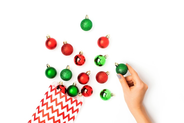 Bolas vermelhas e verdes de Natal fluindo de uma sacola de presente no fundo branco Flat lay, top view trendy holiday concept.