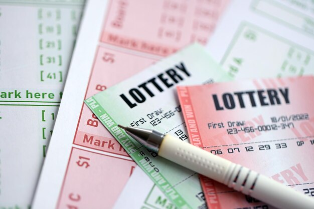 Boletos de lotería verdes y rojos con pluma en billetes en blanco con números para jugar a la lotería