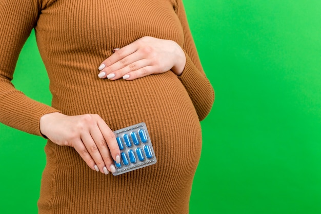 bolha de comprimidos na mão de uma mulher grávida contra a barriga