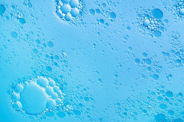 Bolhas de óleo e água sobre fundo azul. Fundo de bolhas de limpador de rosto abstrato
