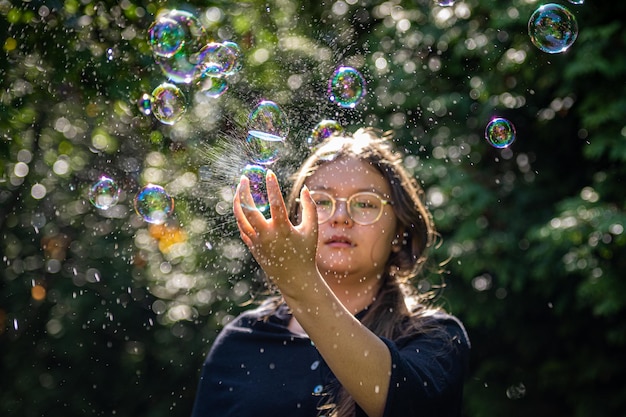 Foto bolhas de sabão e uma mão de uma rapariga pré-adolescente