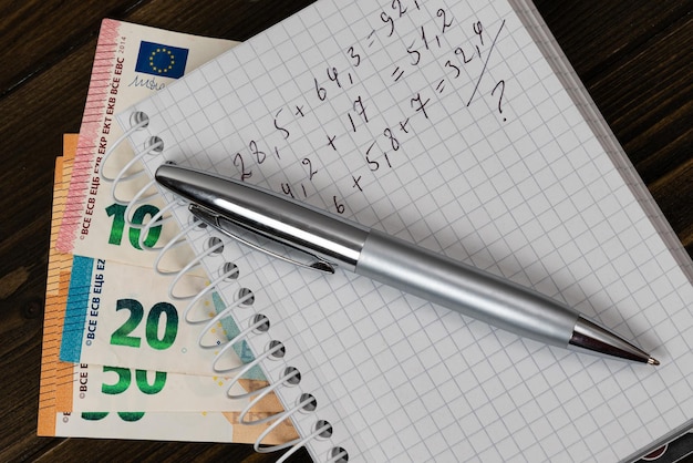 Bolígrafo y billetes con cálculos aritméticos sobre billetes europeos