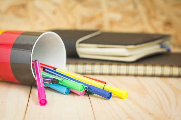 Foto bolígrafo de color con taza y un cuaderno sobre una mesa