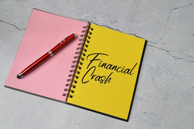 Bolígrafo y cuaderno escrito con CRASH FINANCIERO