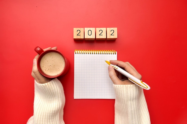 Un bolígrafo, un cuaderno, una taza de café y la inscripción: 2023. Haciendo planes para el nuevo año